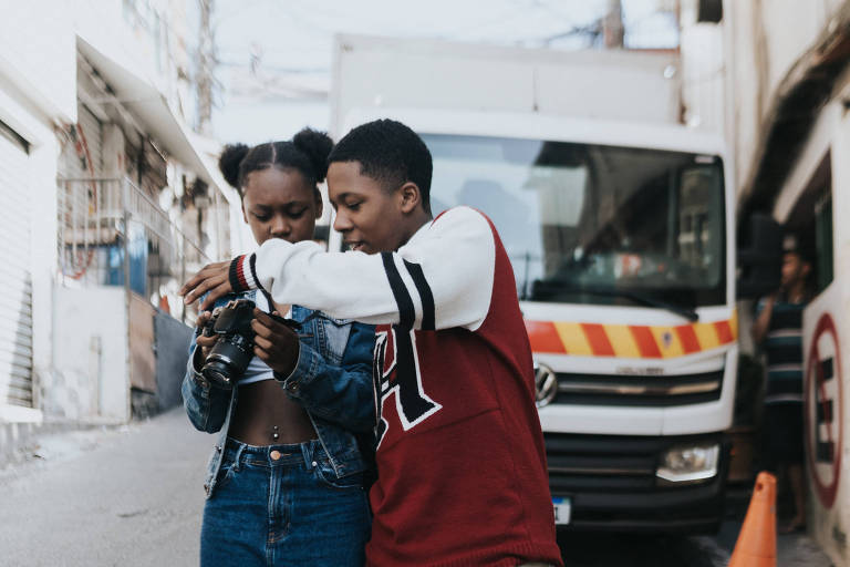 Dois adolescentes negros seguram uma câmera fotográfica 
