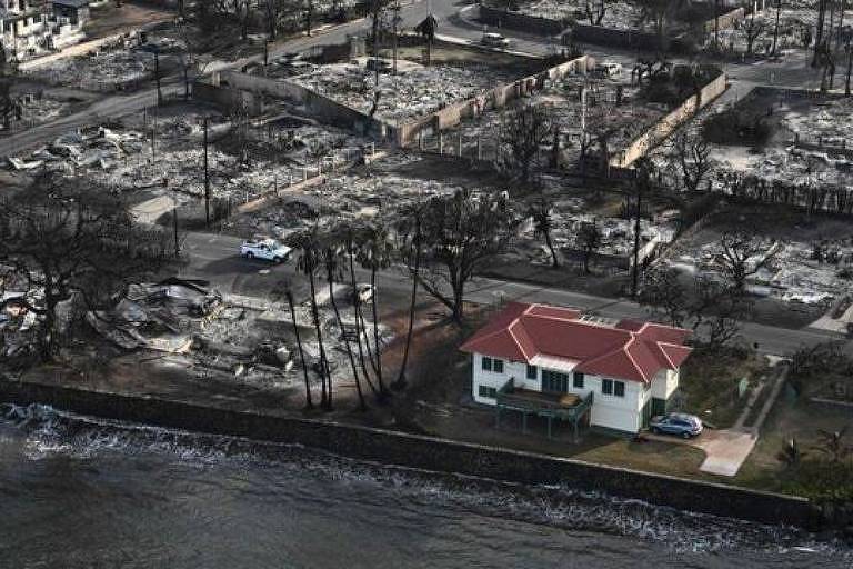 Casa com telhado vermelho e pintura branca permaneceu intacta ao redor de outras casas destruídas pelos incêndios no Havaí