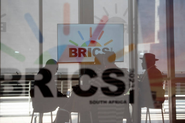 Delegados sul-africanos fazem reunião em sala com vidro adesivado com o logo do Brics