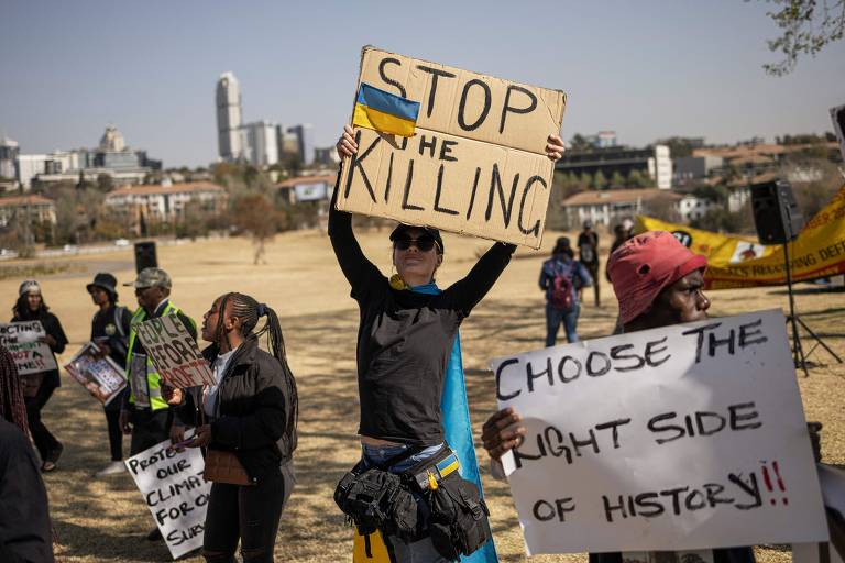 Mulher segurando pequena bandeira da Ucrânia critica ofensiva russa no país vizinho durante cúpula do Brics