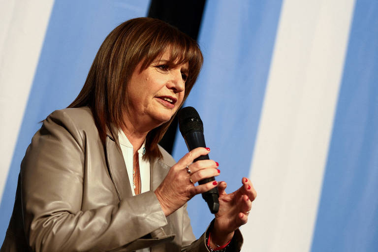 Mulher com microfone na mão e bandeira da Argentina atrás