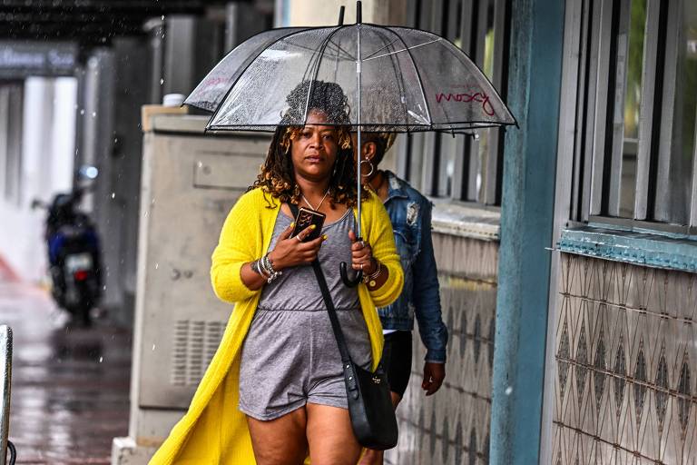 Mulher usa guarda-chuva para se proteger em Miami (EUA)