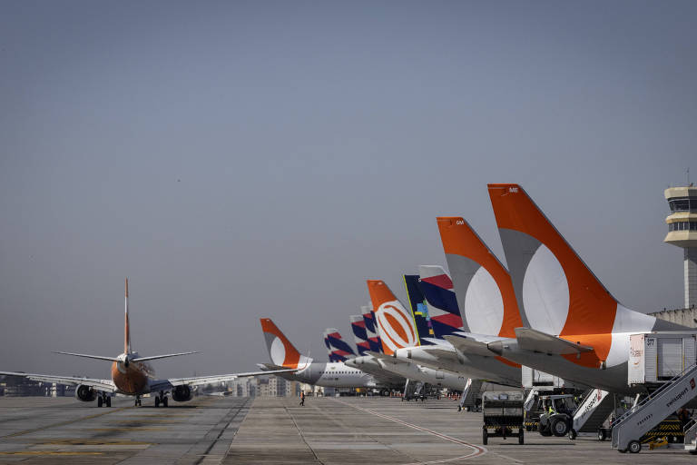 Imagem mostra vários aviões parados na pista de um aeroporto. Um deles se prepara para decolar.
