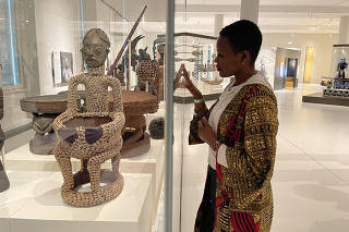 The Cameroonian heritage activist Sylvie Njobati, with a wooden female figure known as Ngonnso, at the Humboldt Forum, in Berlin. (Marc Sebastien Eils via The New York Times)