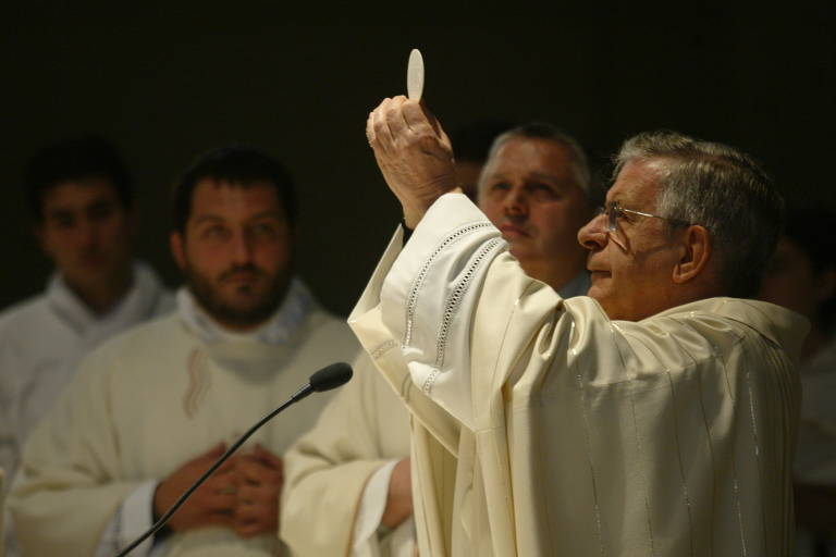Retrato do cardeal de perfil, durante uma missa, segurando uma hóstia nas mãos