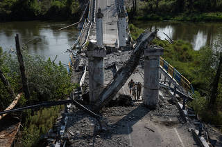 A destroyed bridge that can still be crossed by foot in the village of Bohorodychne, Ukraine, Aug. 22, 2023. (Tyler Hicks/The New York Times)