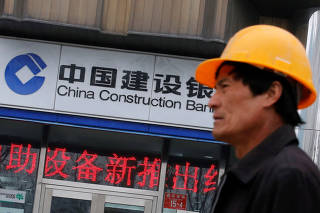 FILE PHOTO: A worker walks past a branch of China Construction Bank (CCB) in Beijing