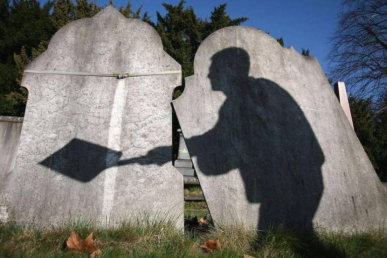 Sombra de homem com pá em cemitério