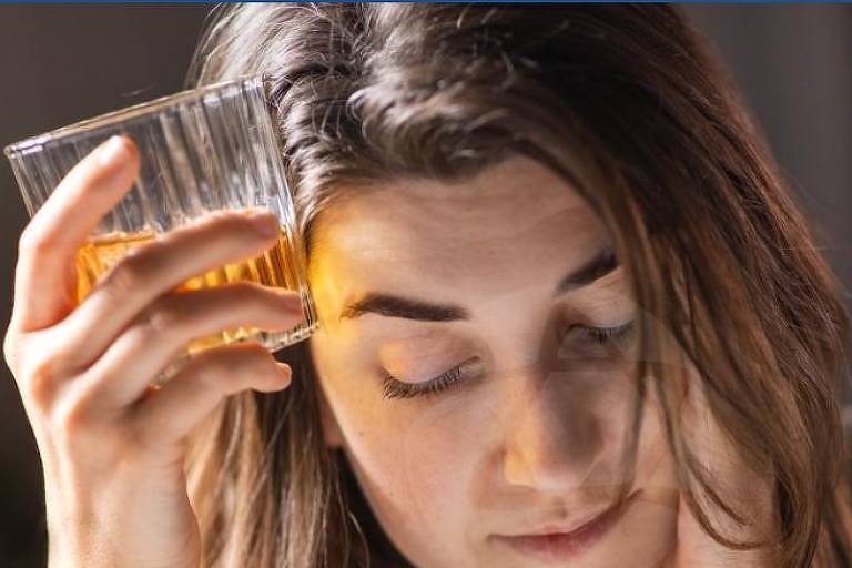 Mulher segura um copo com bebida alcólica