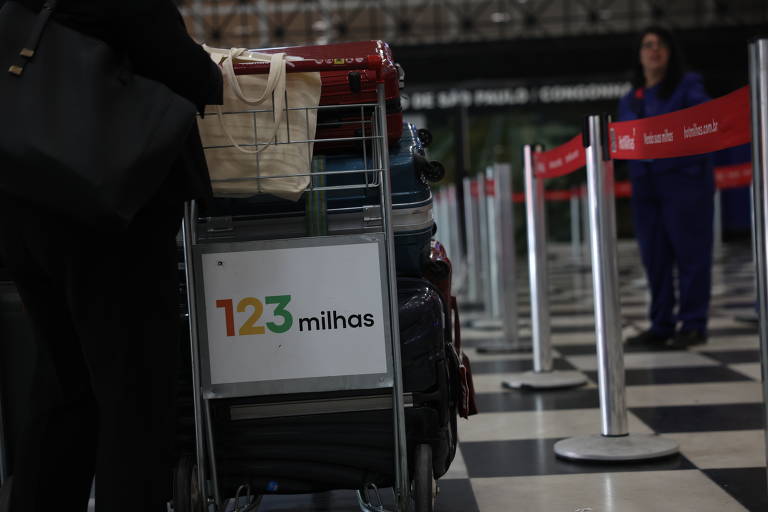 Movimentação no aeroporto de Congonhas, em São Paulo. Pessoa empurra carrinho com publicidade da empresa, cheio de malas.
