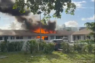 Smoke billows and flames rise inside an apartment complex after a helicopter crashed into it, in Pompano Beach