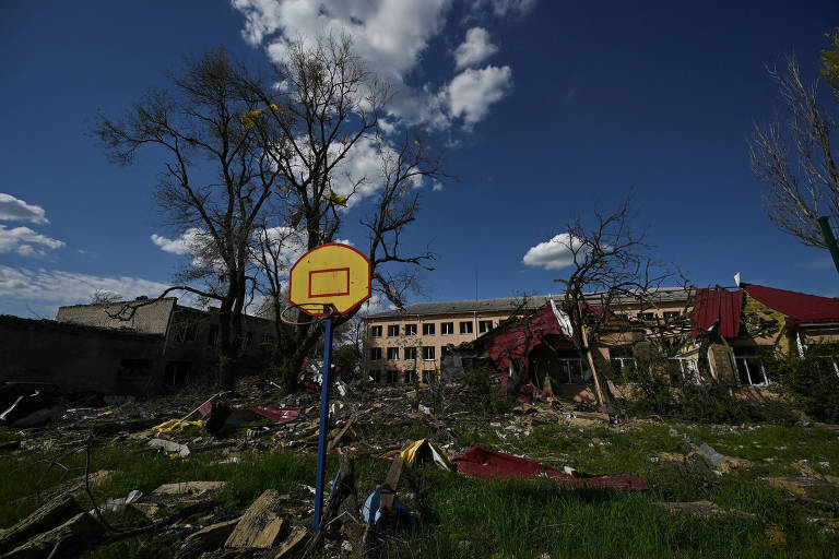 A imagem mostra uma escola destruída, com uma cesta de basquete em primeiro plano