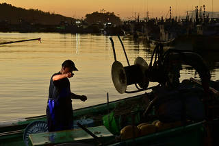 FILE PHOTO: FILE PHOTO: A fisherman works at Matsukawaura fishing port in Soma