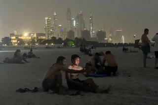 People take a selfie on the beach after sunset as the temperature drops in Dubai.
