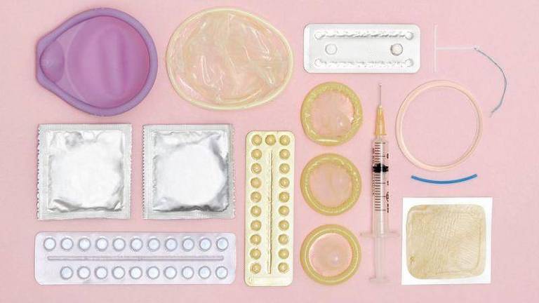 Vários contraceptivos num fundo rosa