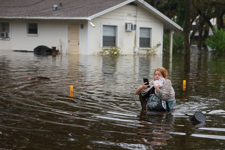 Um mulher atravessa a pé a inundação causada pelo furacão Idalia