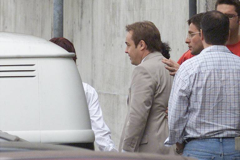 O apresentador do SBT Gugu Liberato (de terno) deixa o Deic após prestar depoimento sobre a falsa entrevista de supostos integrantes do PCC veiculada no programa 'Domingo Legal', em 2003