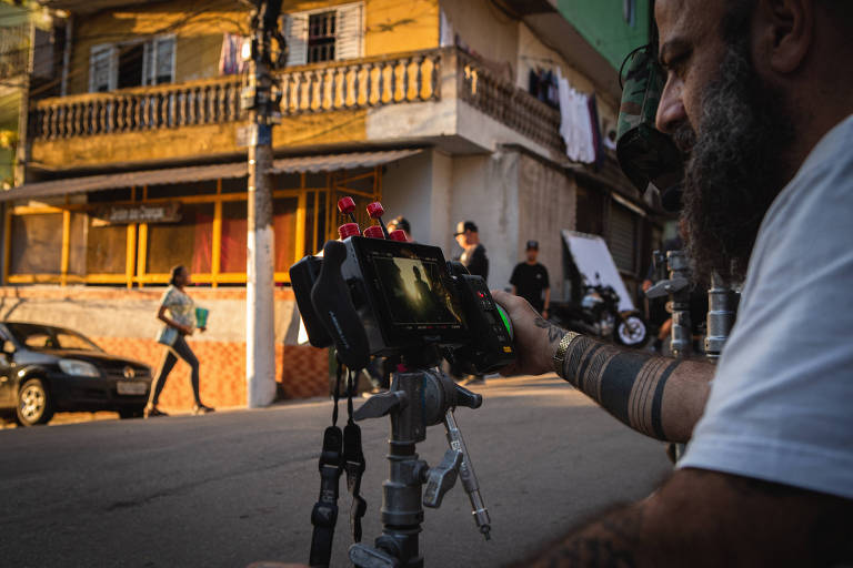 Homem manuseia câmera captando imagens em uma rua aberta