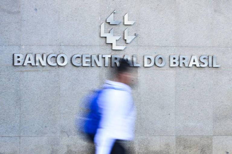 Fachada do Banco Central em que aparece o letreiro com o nome do banco e uma pessoa passa na frente