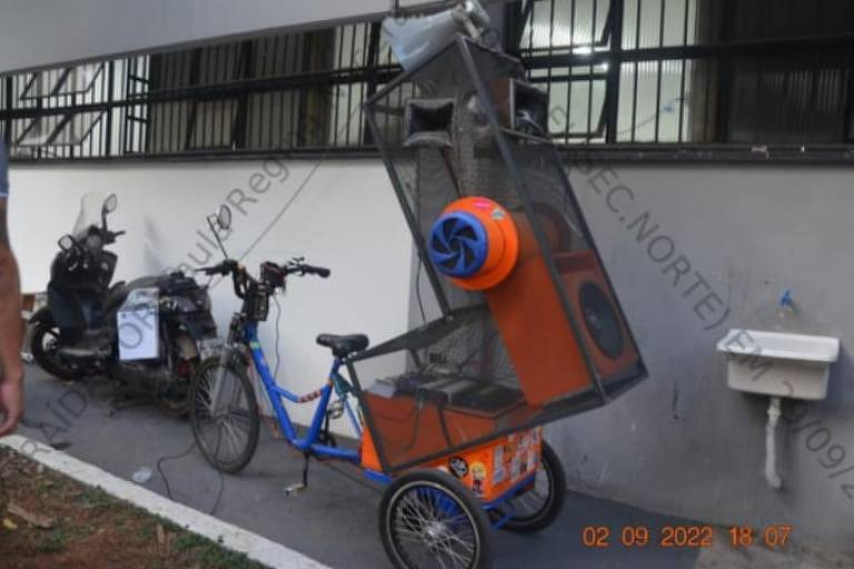 Bicicleta azul e laranja fotografada no pátio da delegacia