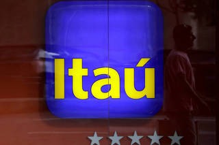 FILE PHOTO: FILE PHOTO: Man is reflected in an Itau branch window in Rio de Janeiro