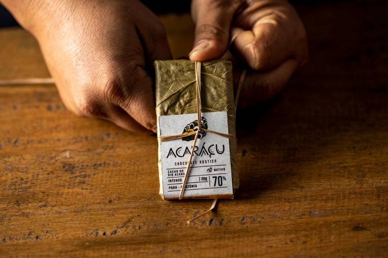 Mão segura pequena barra de chocolate amazônico com embalagem feita da folha do cacau