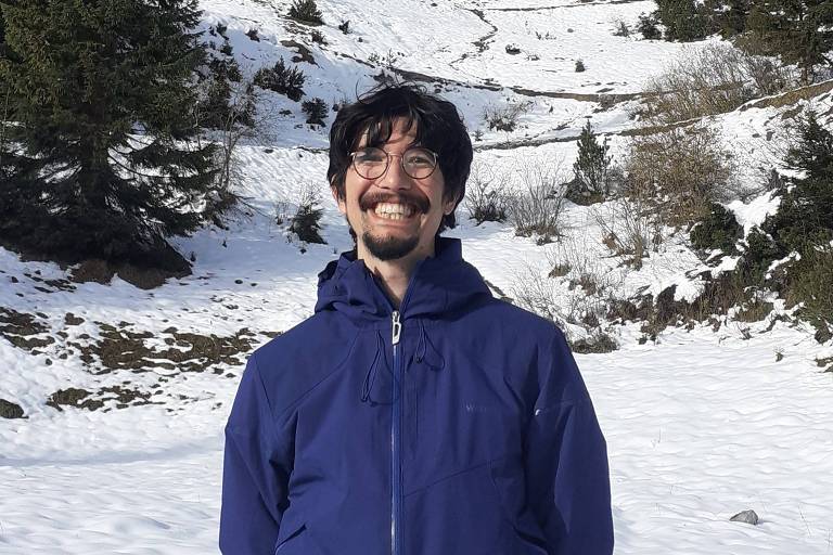 Homem sorri; ao fundo, neve e algumas áreas verdes