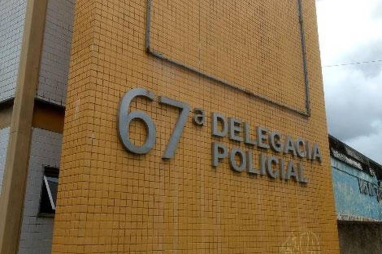 Fachada de delegacia onde o crime foi registrado tem parede de cor amarelho, com letereito que indica 67ª Delegacia de Polícia 