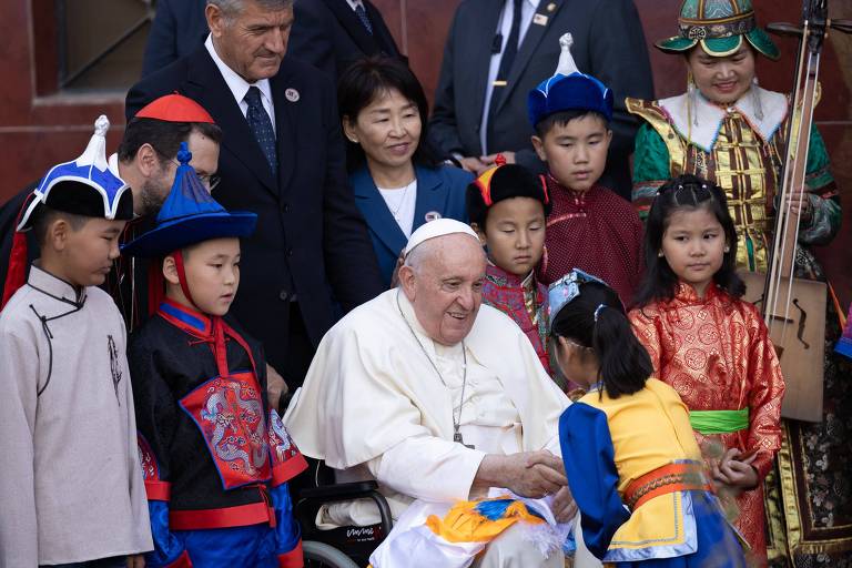 Papa Francisco, vestido de branco e sentado, está cercado de crianças com roupas coloridas em cerimônia para celebrar sua chegada à Mongólia
