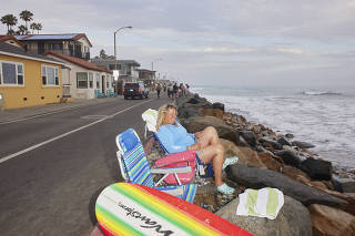 A beachgoer watches the surf from a roadside in Oceanside, Calif., July 31, 2023. (Maggie Shannon/The New York Times)