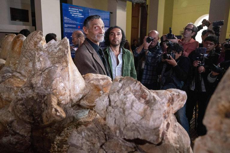 Mario Urbina rodeado de jornalistas e fotógrafos, perto de fósseis
