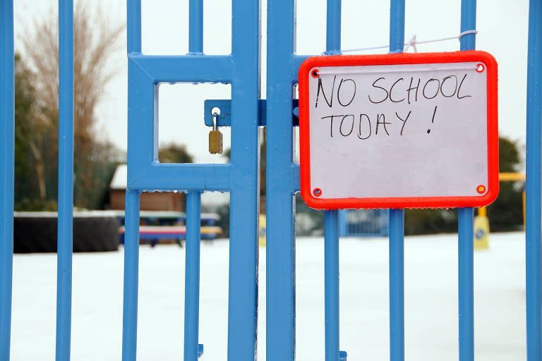Portão com grade azul mostra o aviso: "escola fechada hoje"