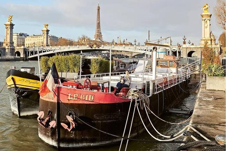 Fotografia colorida mostra uma barcaça no rio Sena