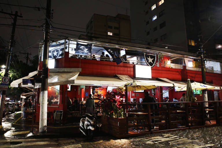 Imagens da parte externa do bar durante a noite e com chuva.
