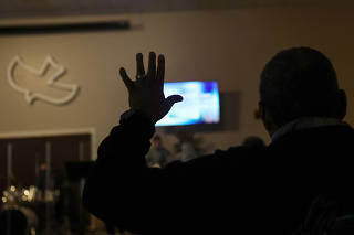 A man raises his hand in worship during Sunday morning church services at Calvary Chapel in Cayce, South Carolina