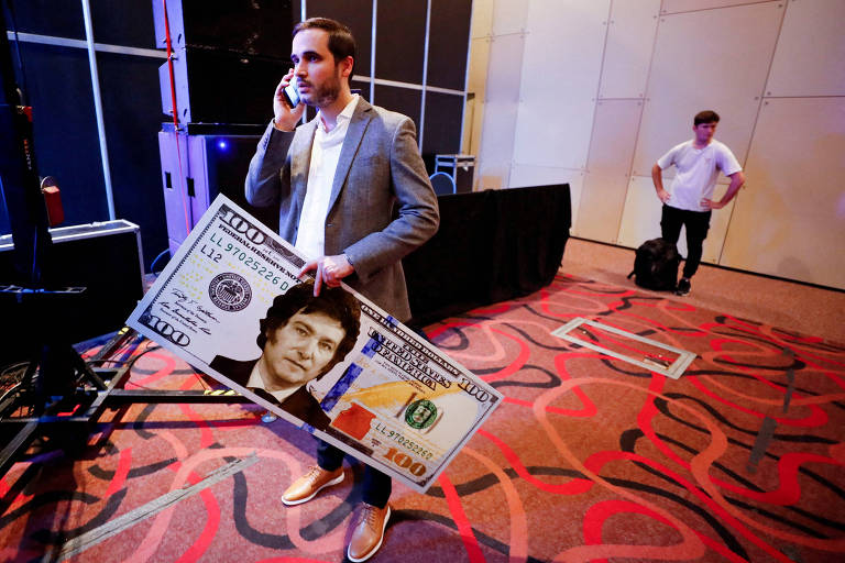 Apoiador de Javier Milei carrega nota gigante de dólar com rosto do candidato à Presidência, que promete dolarizar a economia