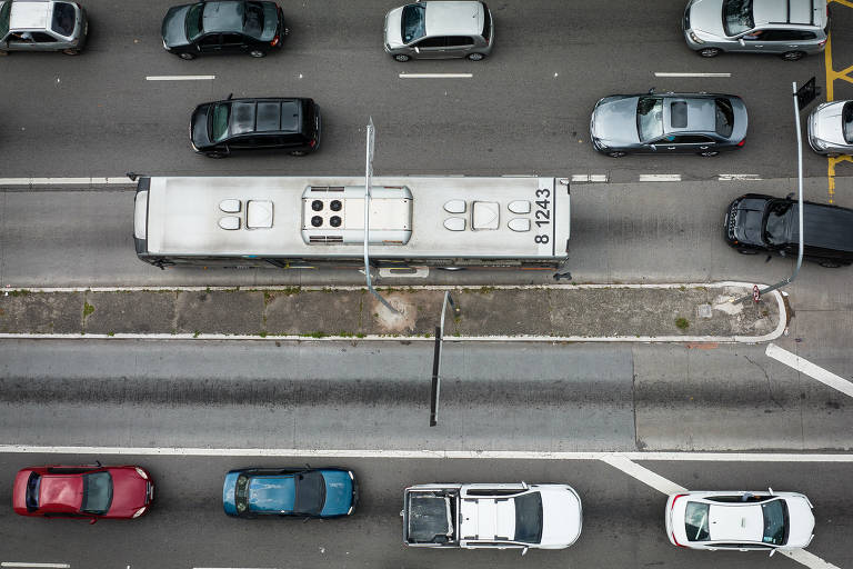 foto aérea mostra teto de veículos variados transitando por pista, como carros ônibus etc