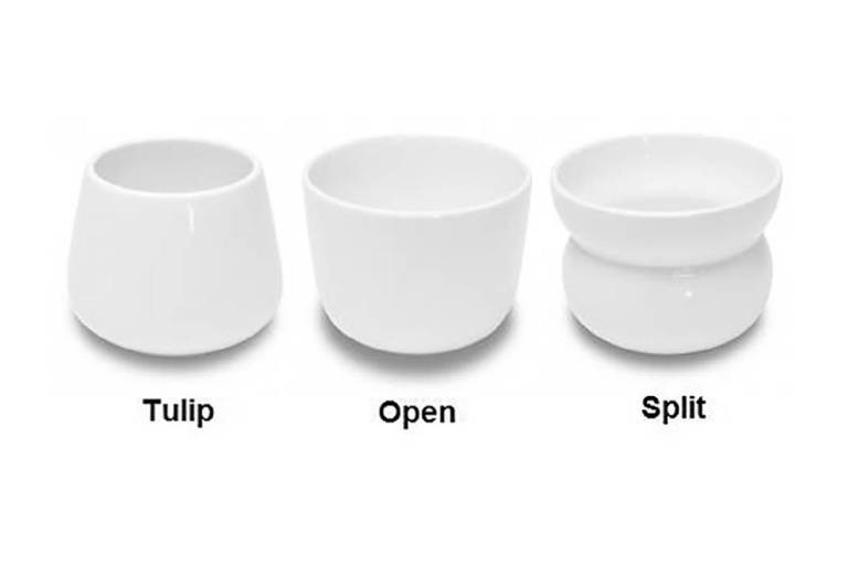 Três xícaras brancas de mesma altura e formatos diferentes; uma tem formato de tulipa; outra tem a boca mais aberta; e a terceira tem uma curva no meio e boca larga