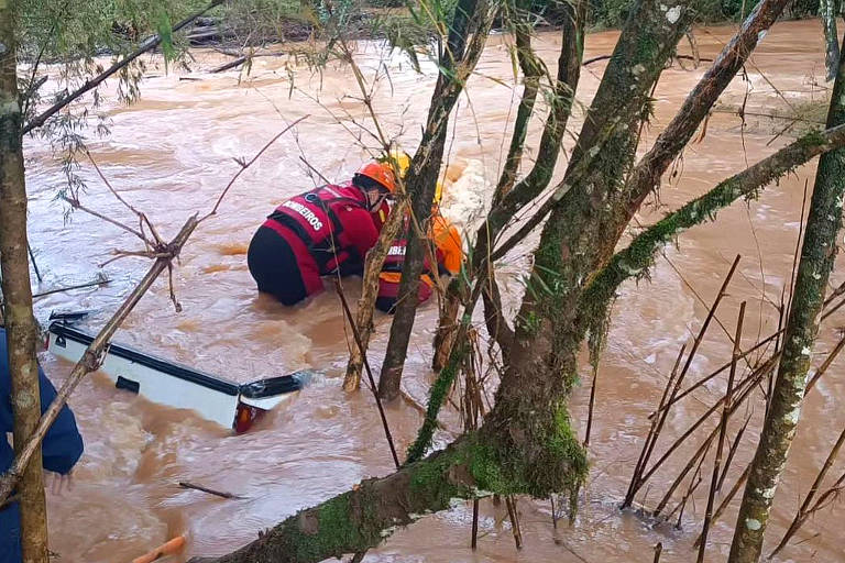Oficiais do Corpo de Bombeiros procuram dentro de uma camionete que ficou totalmente alagada em Passo Fundo