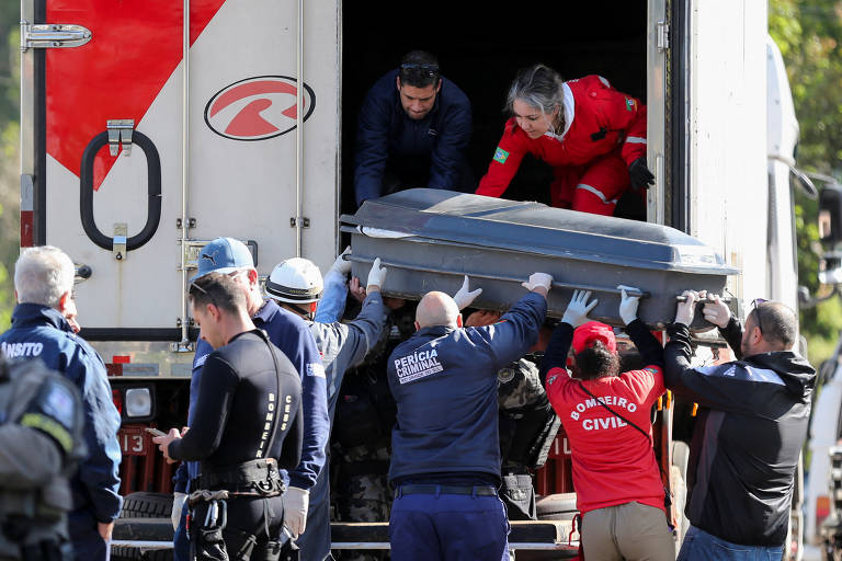 Bombeiros e funcionários do IML colocam caixão de um morto na enchente dentro de um caminhão frigorífico; até esta quarta (6), 32 pessoas haviam morrido em decorrência da tragédia no Sul