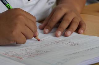 Criança escreve em caderno escolar