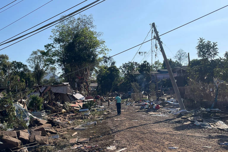 Moradores de Roca Sales (RS), no vale do Taquari, caminham entre postes caídos, casas e carros destruídos pelo temporal na região central do Rio Grande do Sul