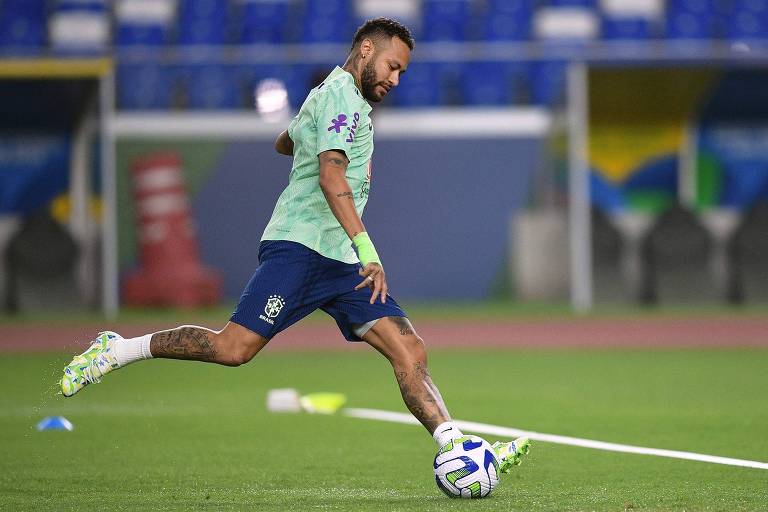 Neymar, de uniforme de treino, chuta a bola com o pé direito