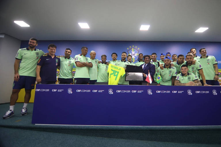 Neymar segura camisa verde e amarela enquanto recebe placa junto a colegas de equipe