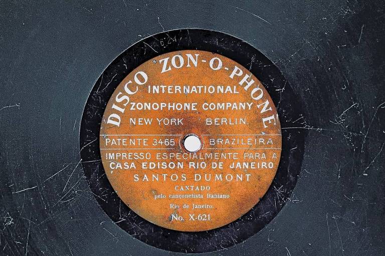 Um disco de música, preto, com um selo cor de laranja no centro  