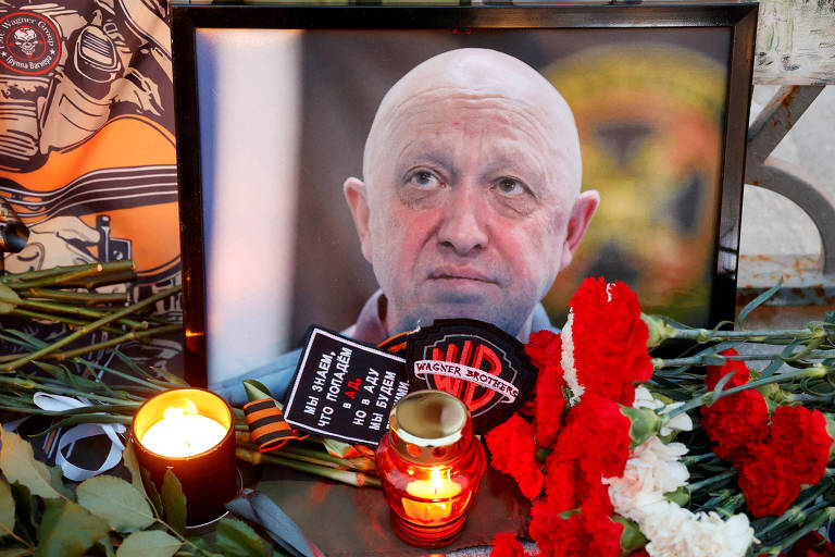 Uma fotografia de Yevgeny Prigozhin com flores e velas