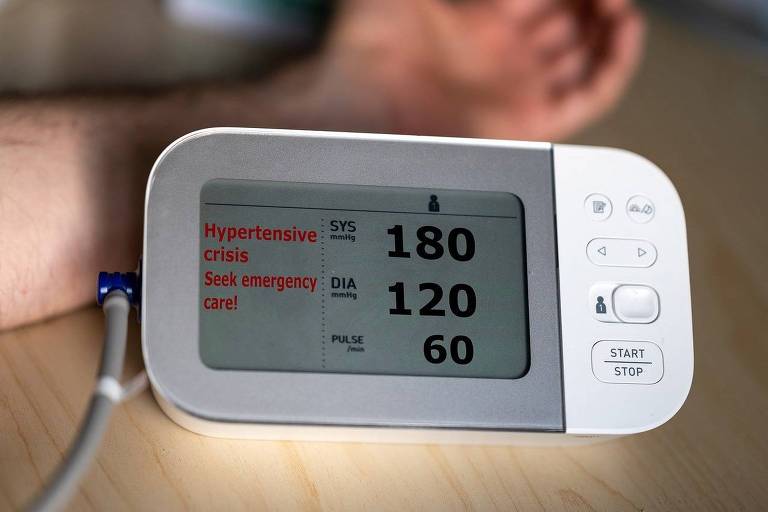 Homem branco realiza exame de hipertensão com medidor automático