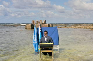 Tuvalu's Foreign Minister Simon Kofe gives a COP26 statement while standing in the ocean, in Funafuti