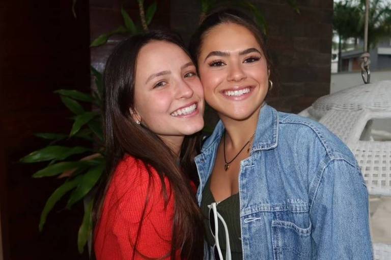 Em foto colorida, duas mulheres aparecem juntas sorrindo para foto