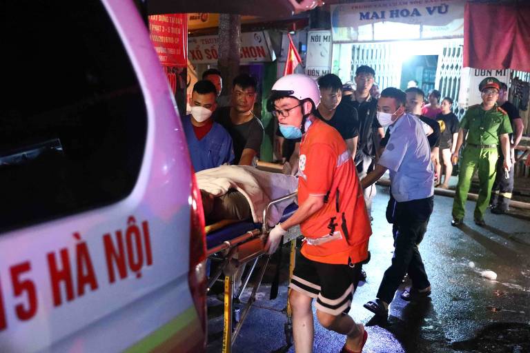 Socorristas levam vítimas do incêndio em edifício de Hanói para ambulância 